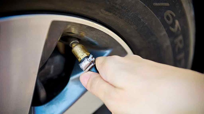 person pumps car tyre with air compressor